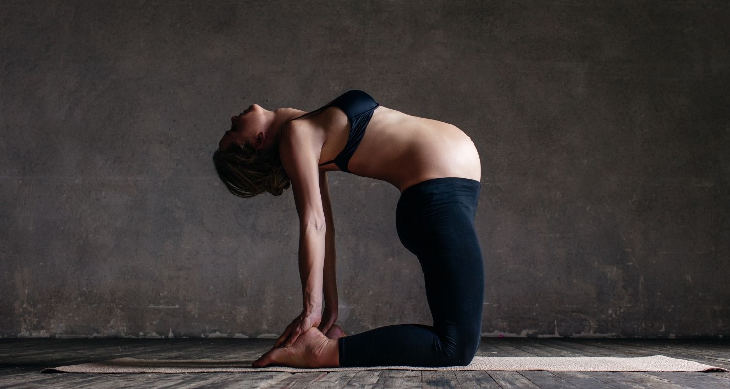 A young pregnant girl performs a yoga pose